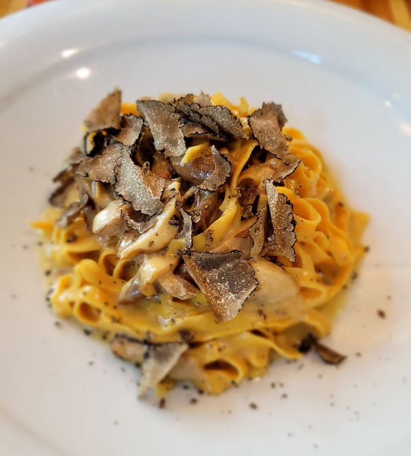 Pasta dish topped with mushrooms on white plate